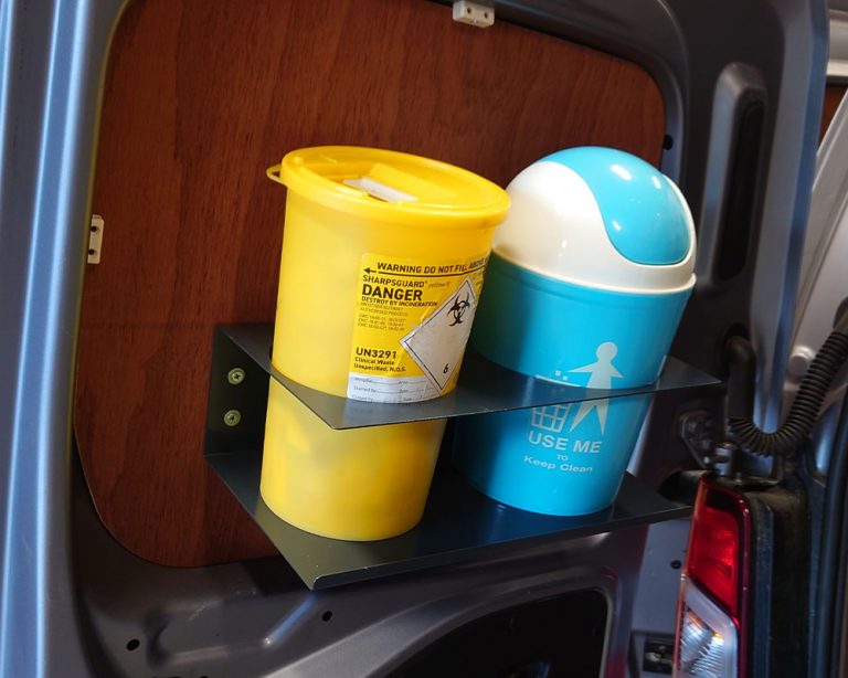 waste bin and clinical waste bin in the back of a van, attached to the door with a shelving unit